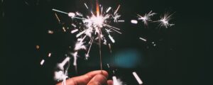 Eine Hand hält eine leuchtende Wunderkerze, Symbol für einen hoffnungsvollen Start und neue Ziele im neuen Jahr.